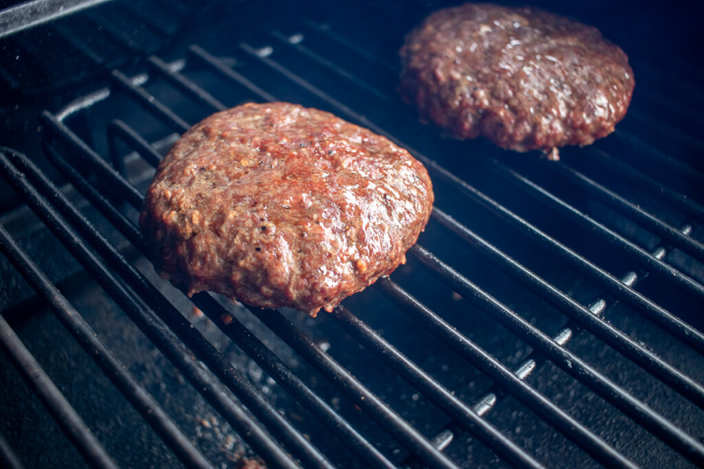a burger patty on the smoker looking juicy