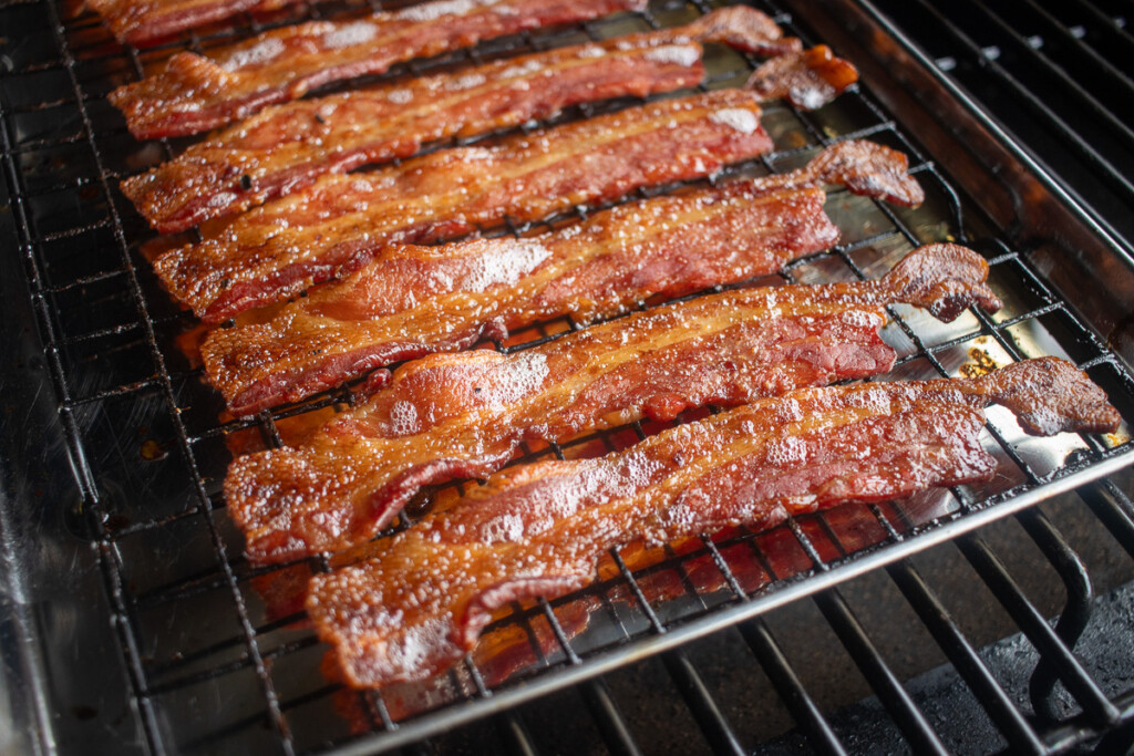 a tray of bacon cooking on the smoker