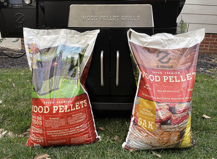 two full bags of wood pellets beside a pellet grill