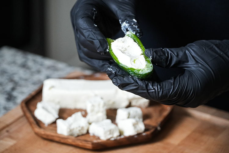 a hand holding half a jalapeño stuffed with cream cheese