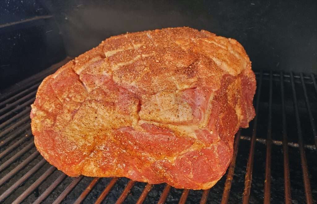 Seasoned pork butt in a smoker