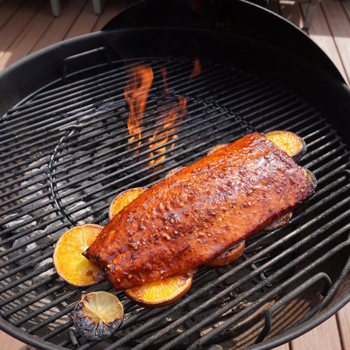 citrus salmon cooked on the grill on a bed of sliced oranges and limes.