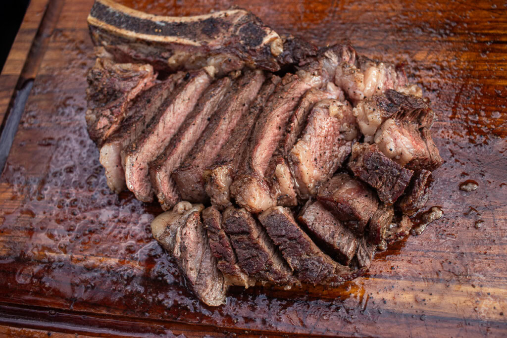 cooked, sliced ribeye steak on a wooden board