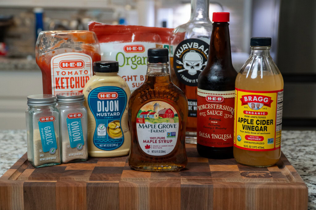 all the ingredients for maple bourbon bbq sauce displayed on a wooden board