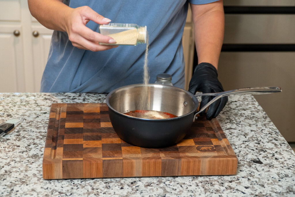 a person sprinkling some seasoning into a metal bowl