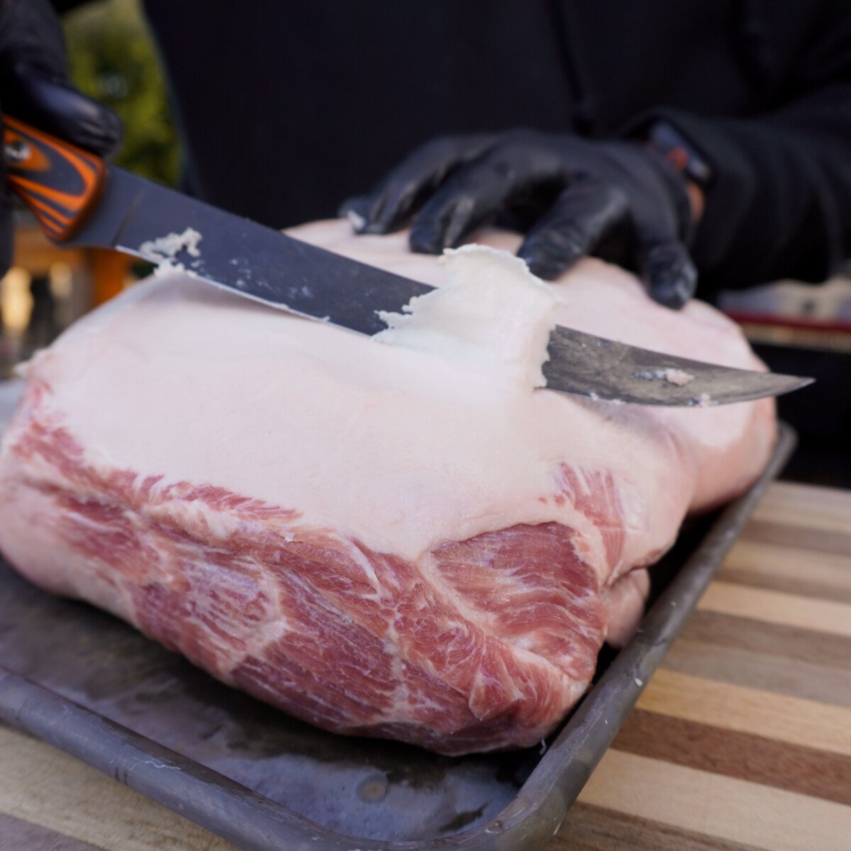 Trimming fat off a pork shoulder.