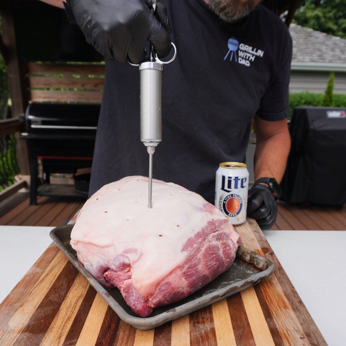 Injecting beer into a pork shoulder.
