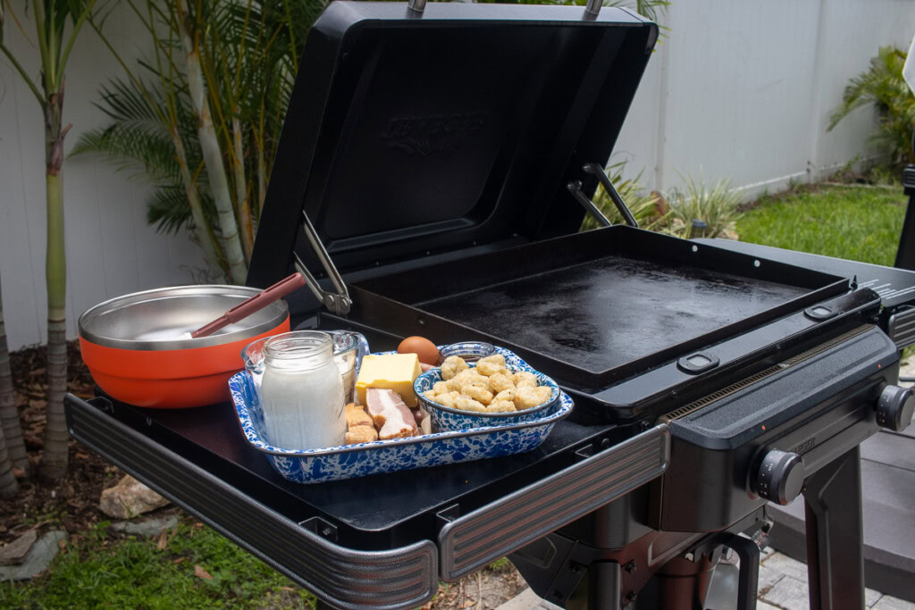 a tray sitting on the side of the griddle with all the food prepped and ready to be cooked