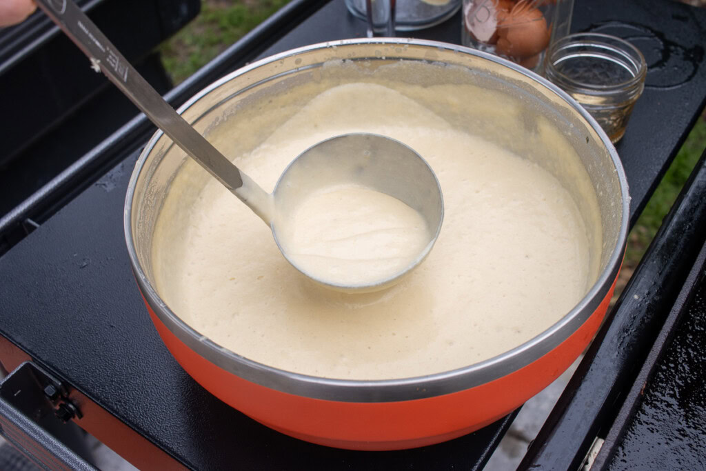 an orange bowl with a ladle and pancake mix in it