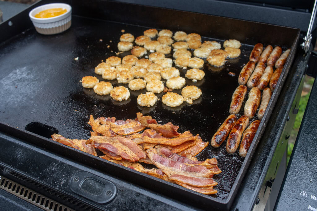 cooked crispy bacon, sausage and hash browns on the griddle
