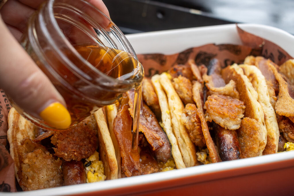 a jar of honey being drizzled over pancake breakfast tacos