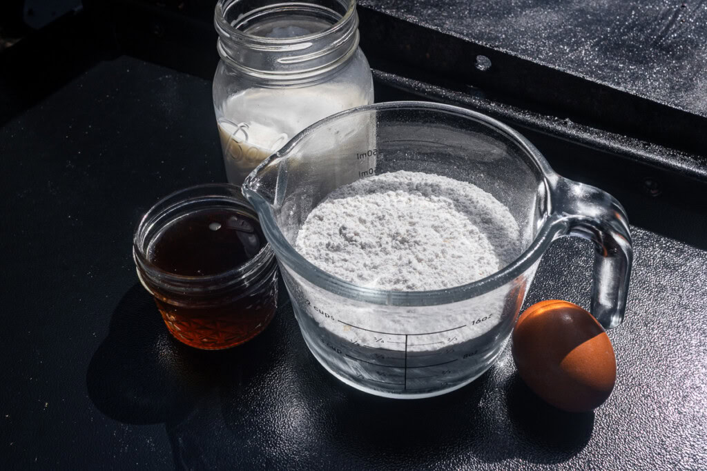 a jar of milk, a jar of maple syrup and a measuring jug of dry pancake mix