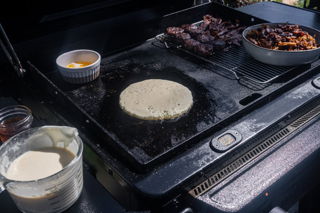 a raw pancake on the griddle with bubbles, ready to turn