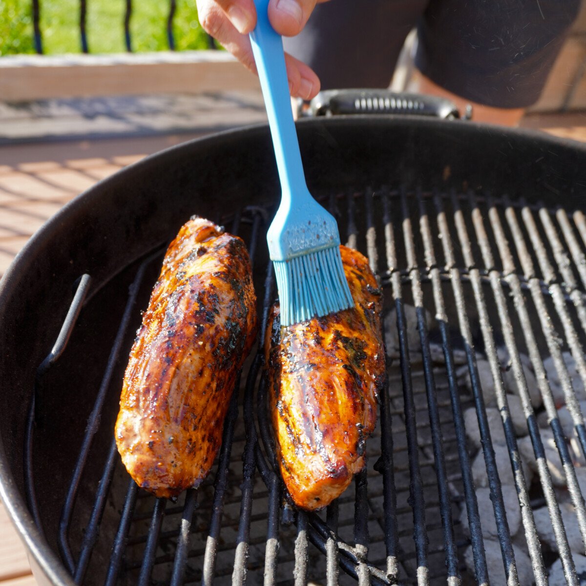 brushing sweet and savory marinade over grilled pork tenderloin.