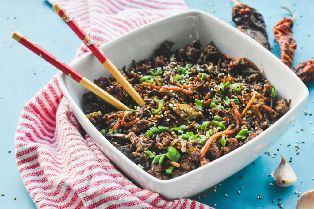A bowl of keto egg roll in a bowl with two chopsticks sticking out.