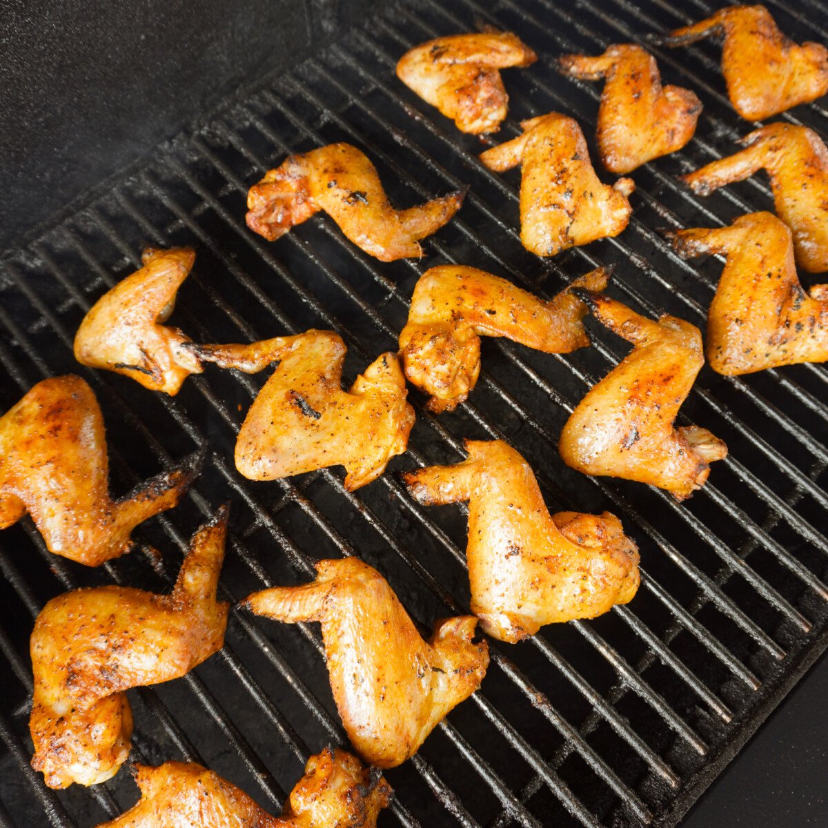 chicken wings being grilled over indirect heat on a grill.