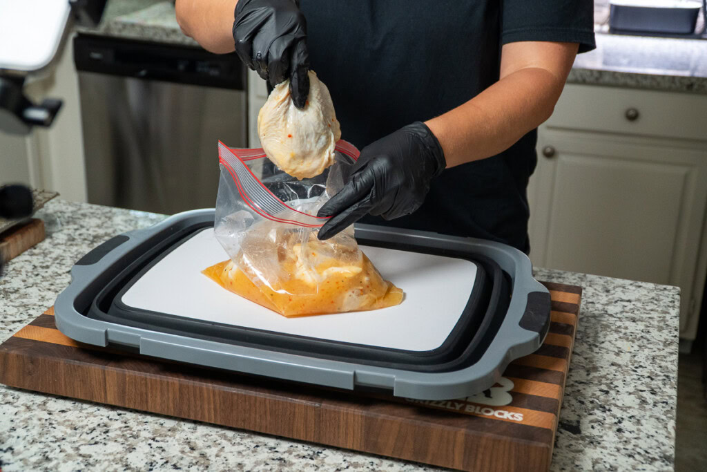 chicken thighs being added to a bag of marinade