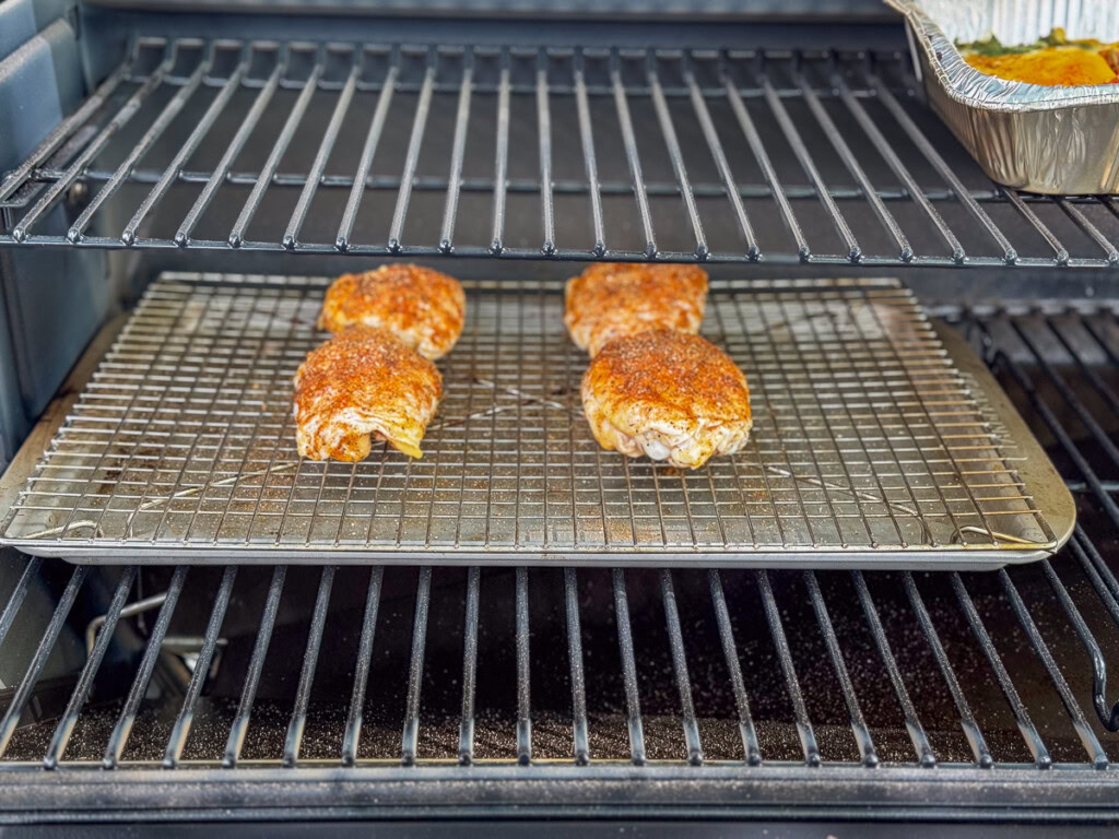 raw seasoned chicken thighs in the smoker