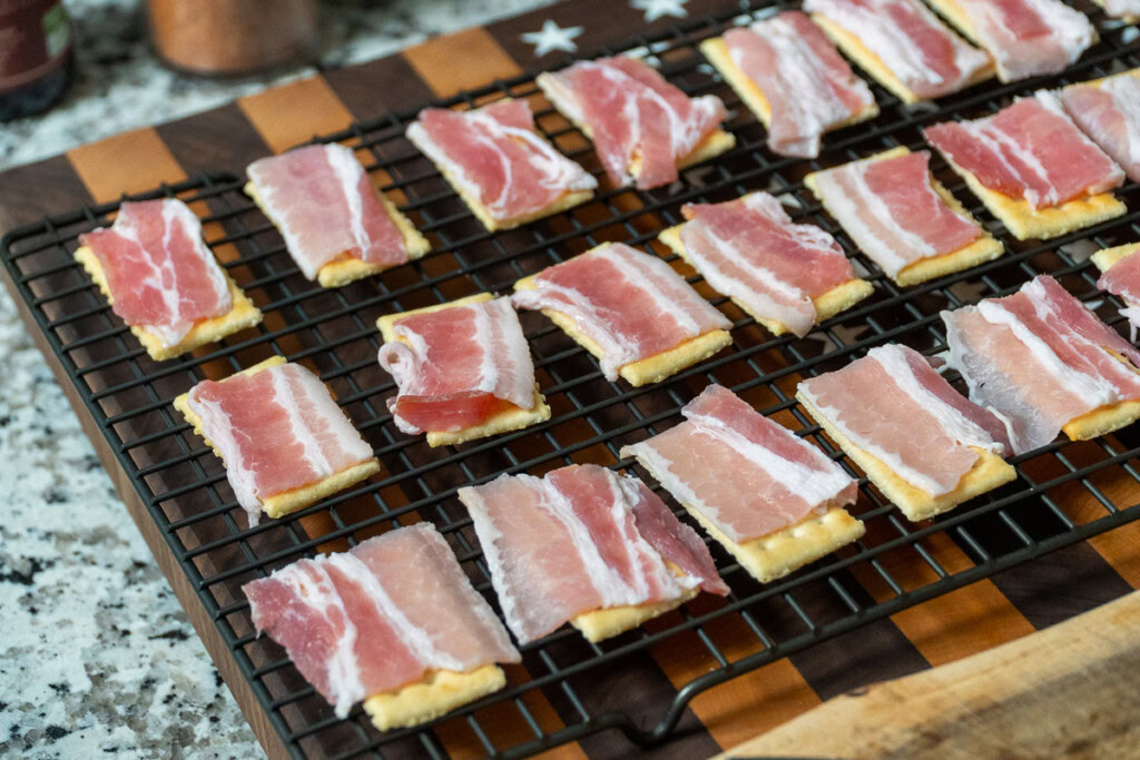 crackers on a wire rack with a piece of bacon on top