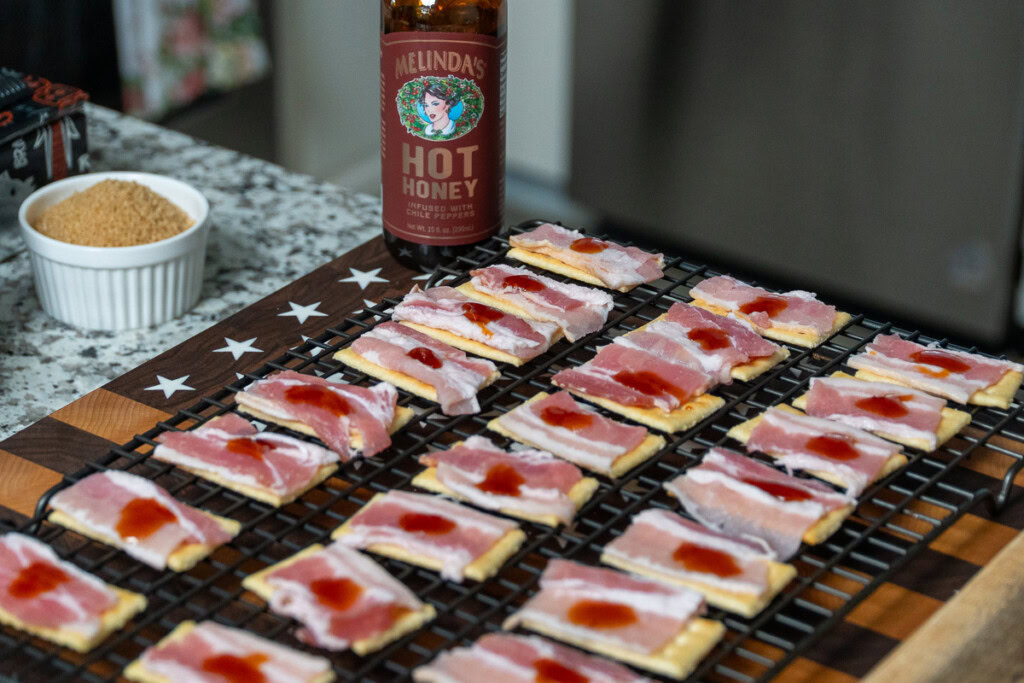 a drop of hot honey on each cracker covered in bacon