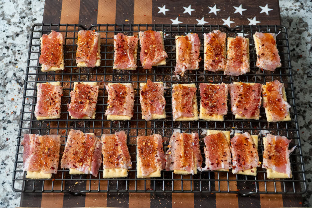 seasoned bacon topped crackers on a wire rack