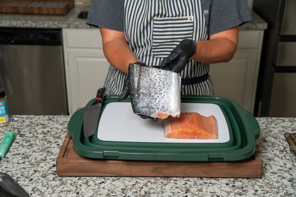 a person is holding a piece of raw salmon with the skin side facing out