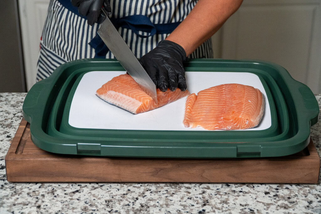 a person is slicing into a piece of raw salmon