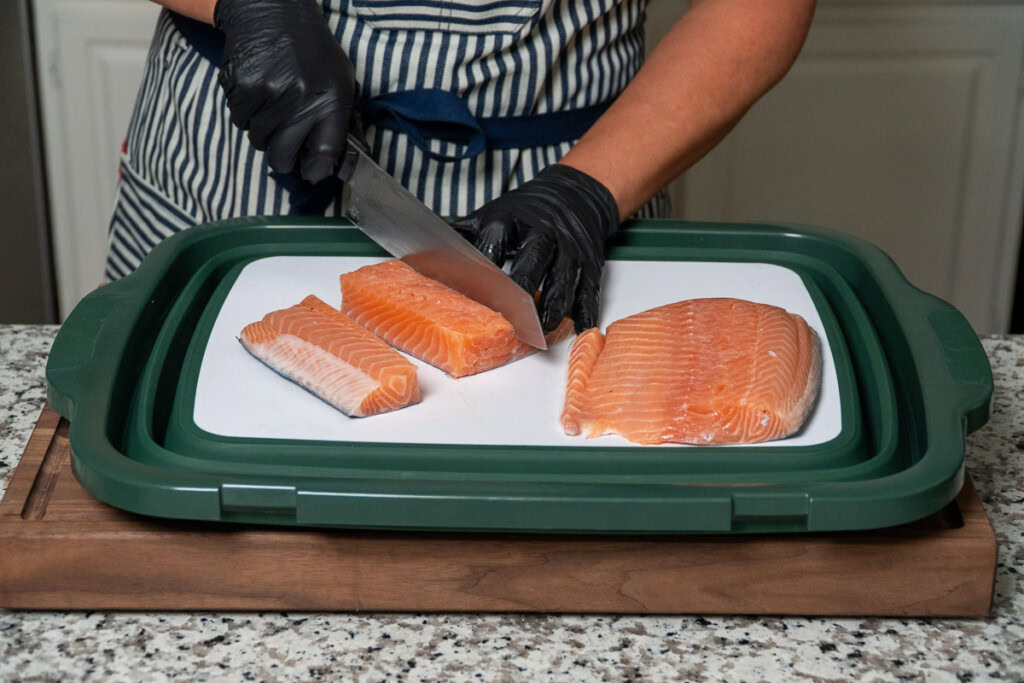 a person is making slices of raw salmon