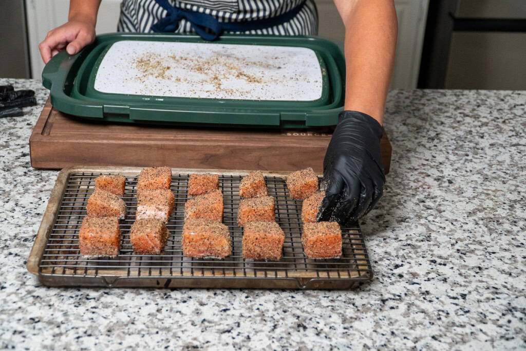 a wire rack with cubes of seasoned raw salmon on it