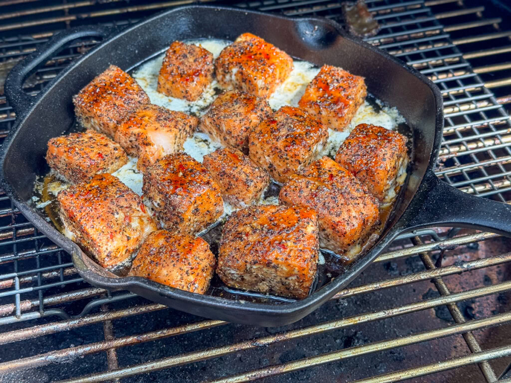 a cast iron skillet filled with cooked smoked salmon burnt ends