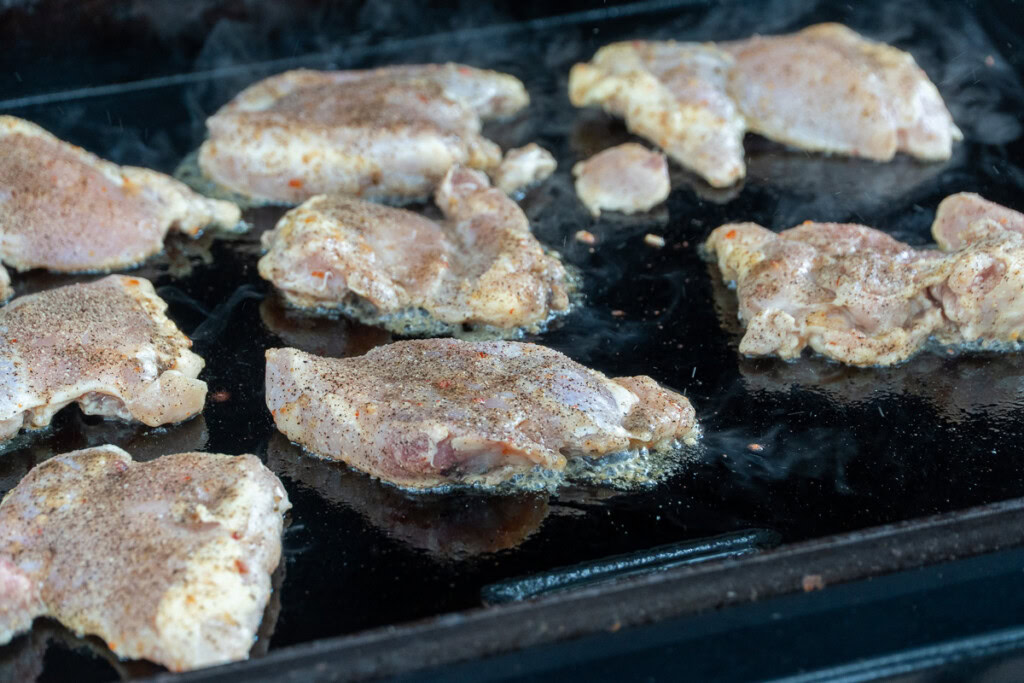 raw seasoned chicken thighs on the griddle