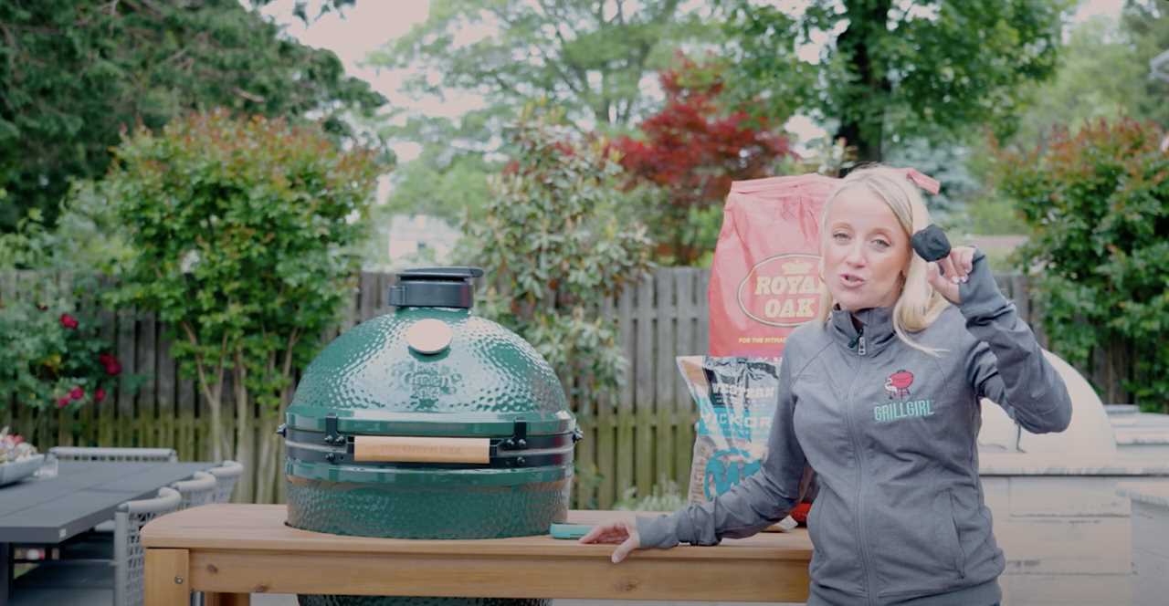 A female chef grilling outside, holding a piece of charcoal.