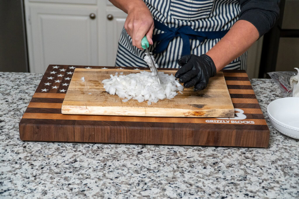 a person dicing up raw white onion
