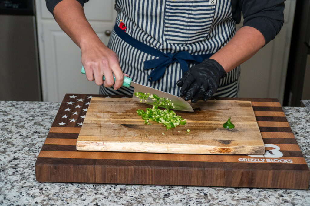 a person dicing up raw jalapeno
