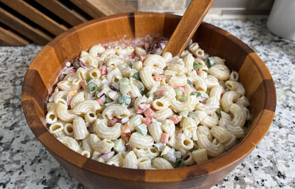 macaroni salad in a wooden bowl with a serving spooin in it