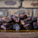 Smoked poor man’s burnt ends made from beef chuck roast, stacked on a wooden board with a dark bark and juicy interior.