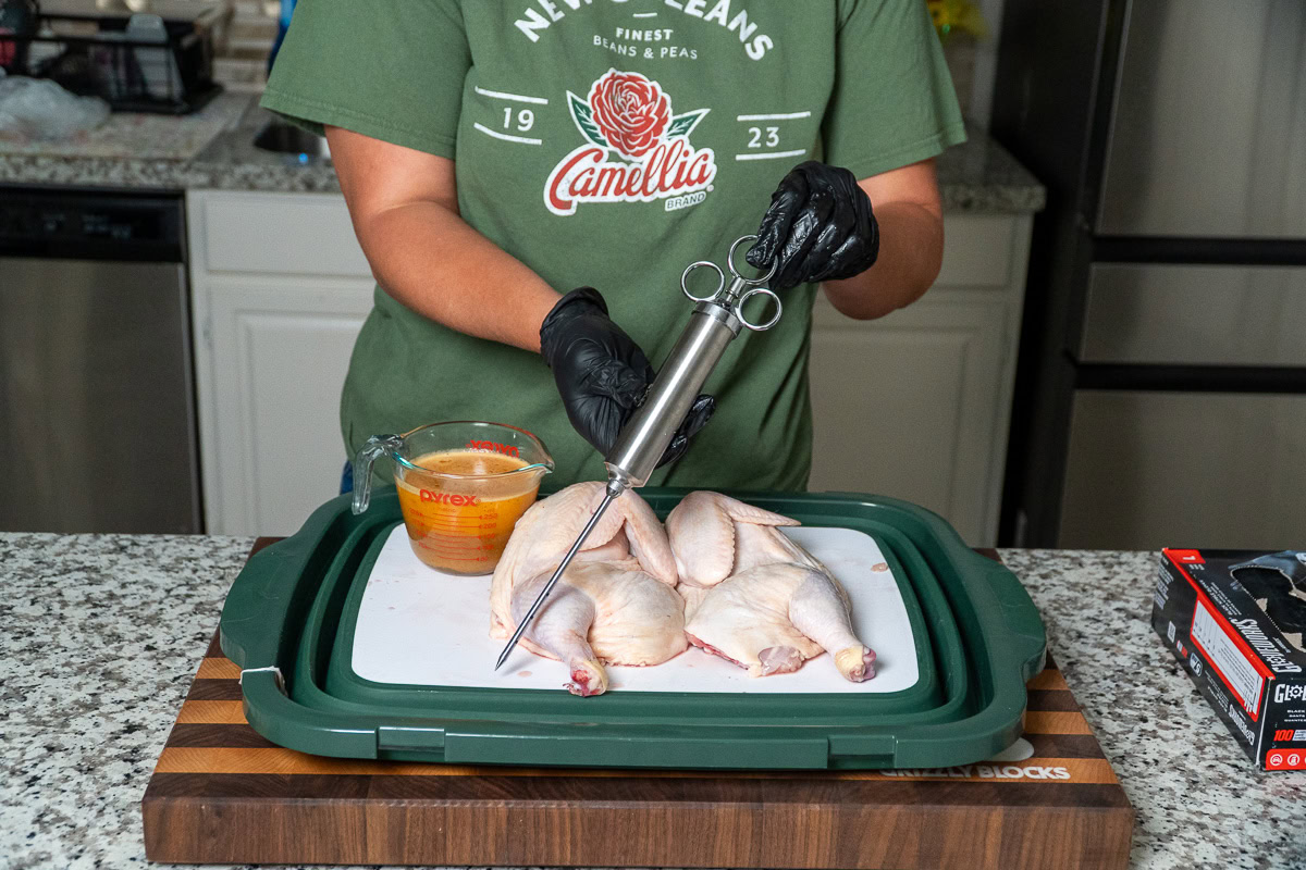 a person holding an injector getting ready to inject a raw chicken
