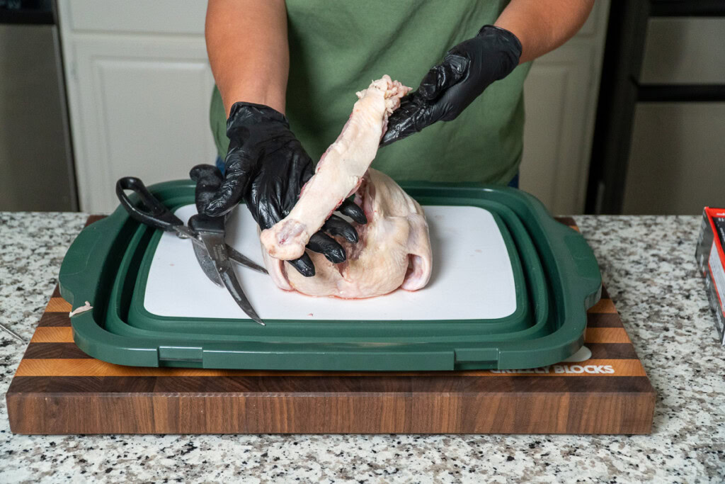 a person holding the backbone they just cut out of a raw chicken