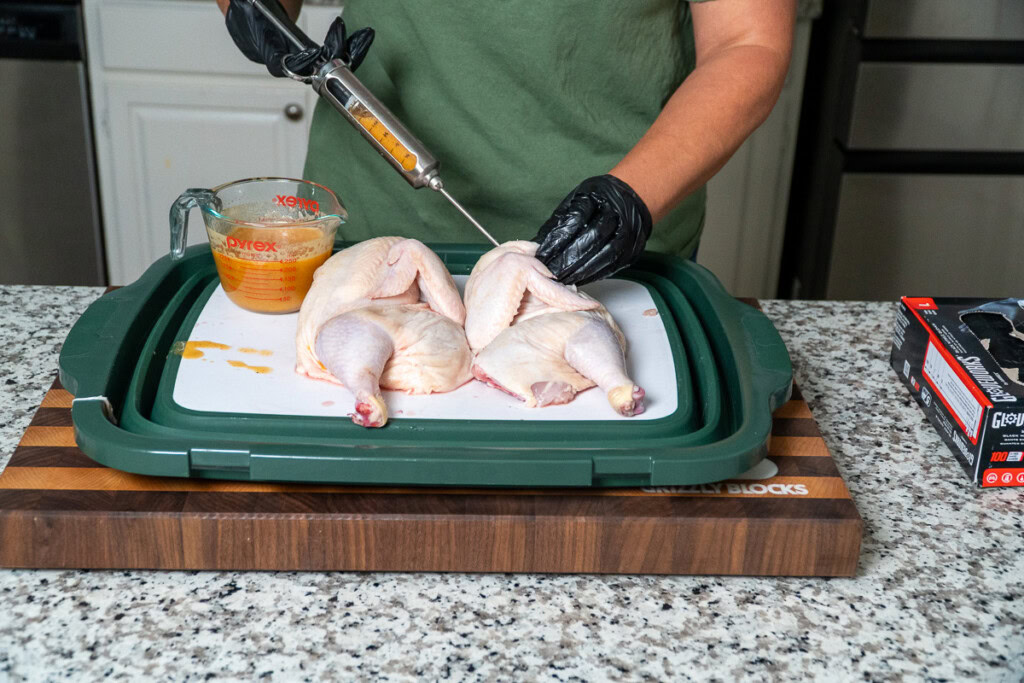 a person injecting a raw chicken with juicy goodness