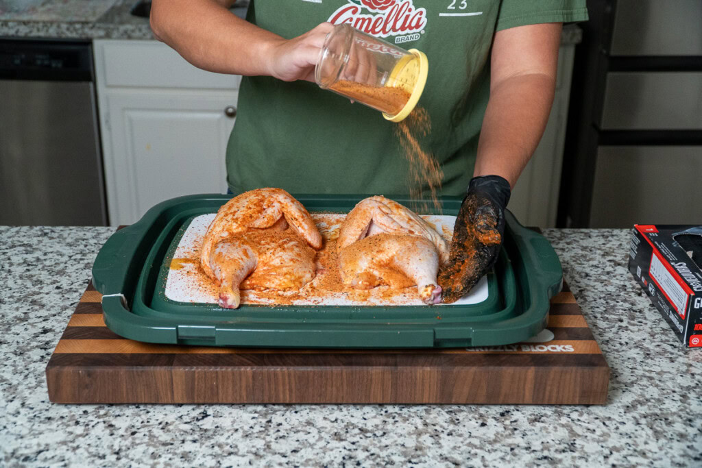 a seasoned, raw, halved chicken 