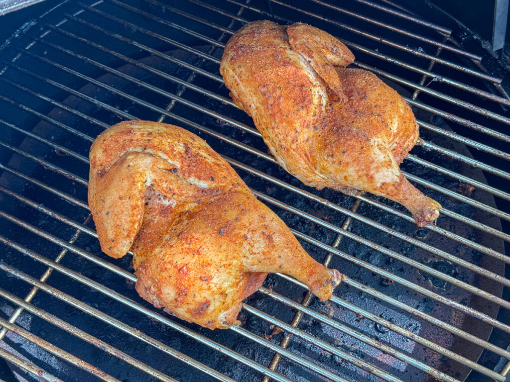 two chicken halves on the smoker cooking