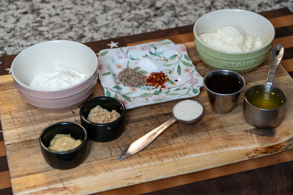 the ingredients for the salad dressing displayed on a wooden board