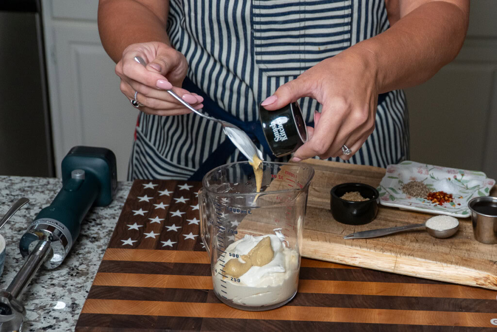 dijon mustard being put in a jug with mayo and sour cream