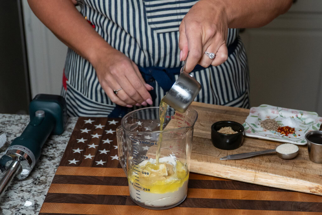 oil being tipped into the jug with the salad dressing ingredients