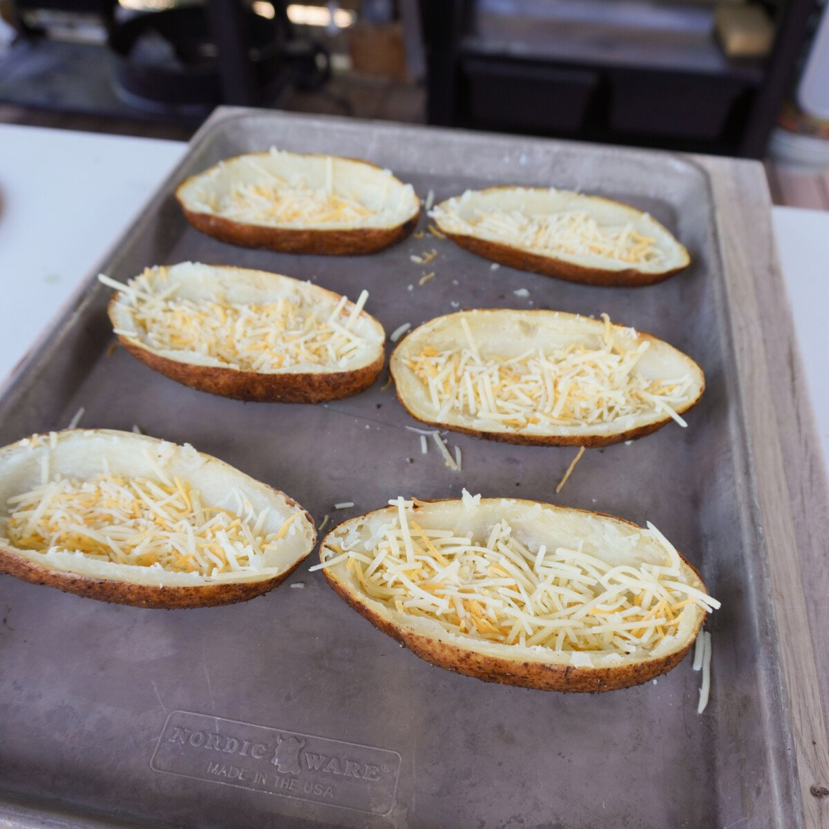empty potato skins with shredded cheese on the bottom.