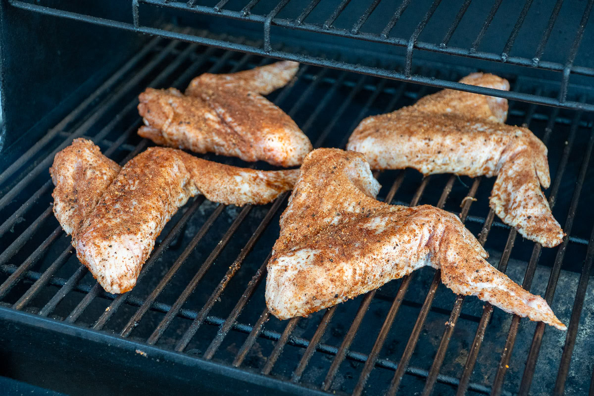 raw seasoned turkey wings on the smoker