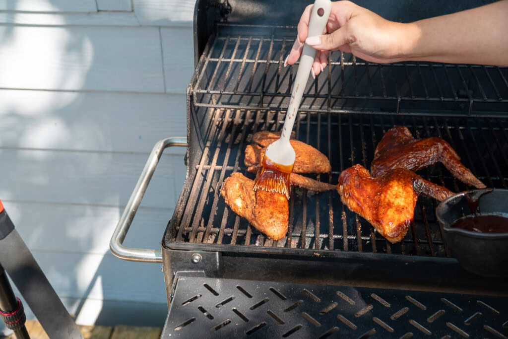 a person basting smoked turkey wings with sauce