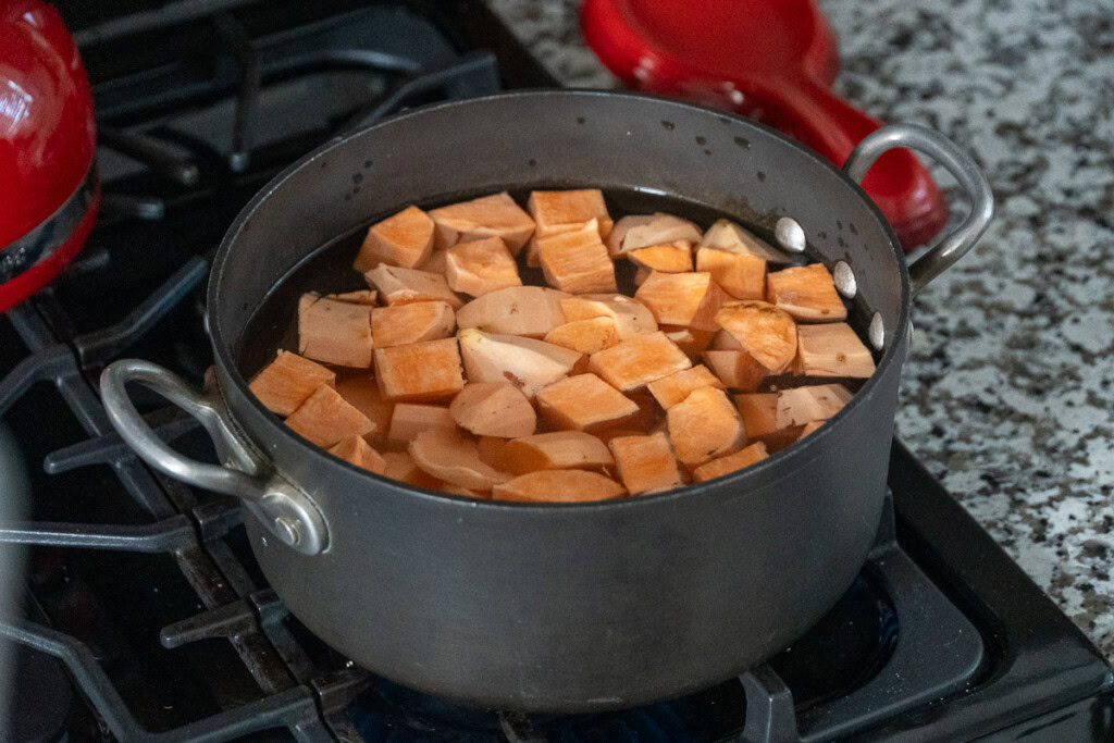 a pot full of water and raw sweet potatoes on cook top