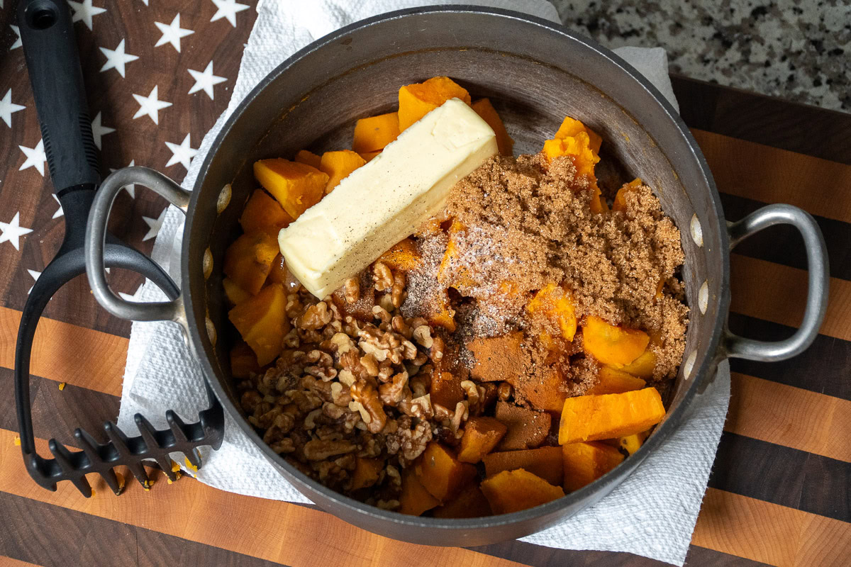 cooked sweet potatoes in a pot with butter and spices ready to be mashed