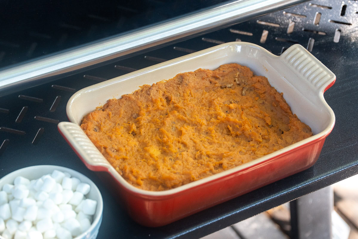 mashed sweet potatoes in a casserole dish in the smoker ready for the marshmellows